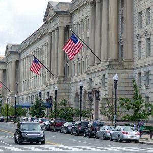 Federal agency building with American flag and car parked alongside